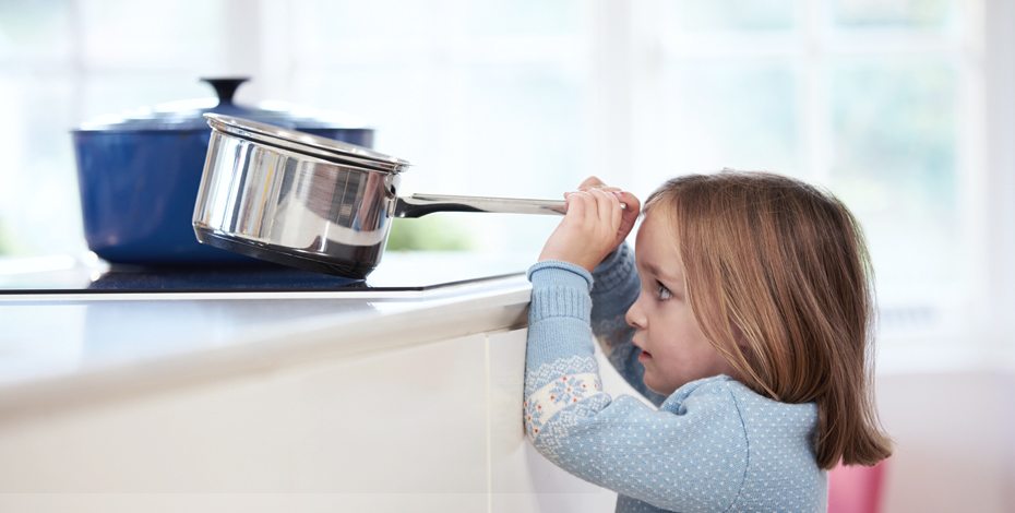Kind in der Küche beim Spielen mit einem Topf